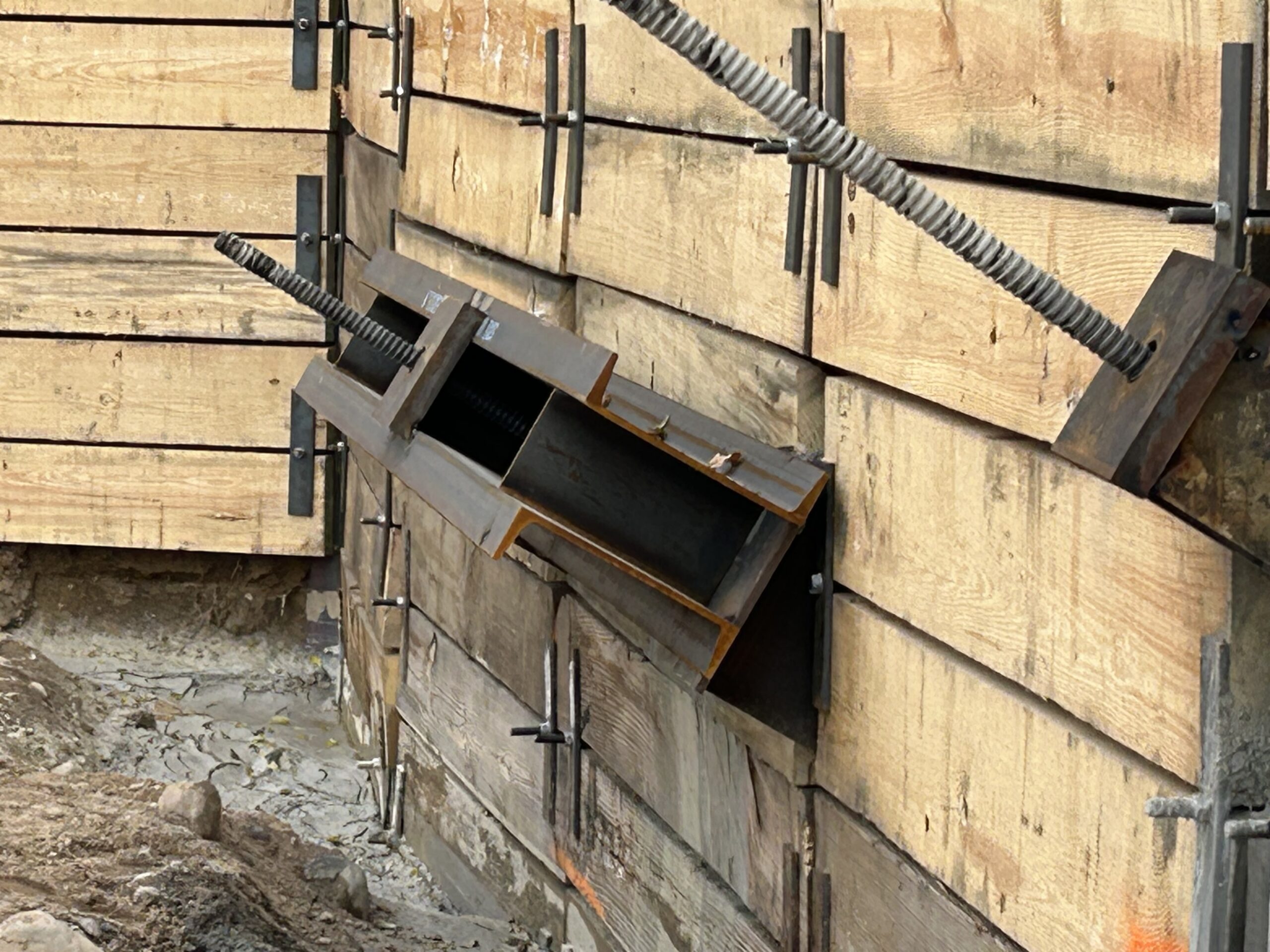 Wooden formwork for concrete construction with held-in steel tie rods and spiral rebar rods projecting outward.