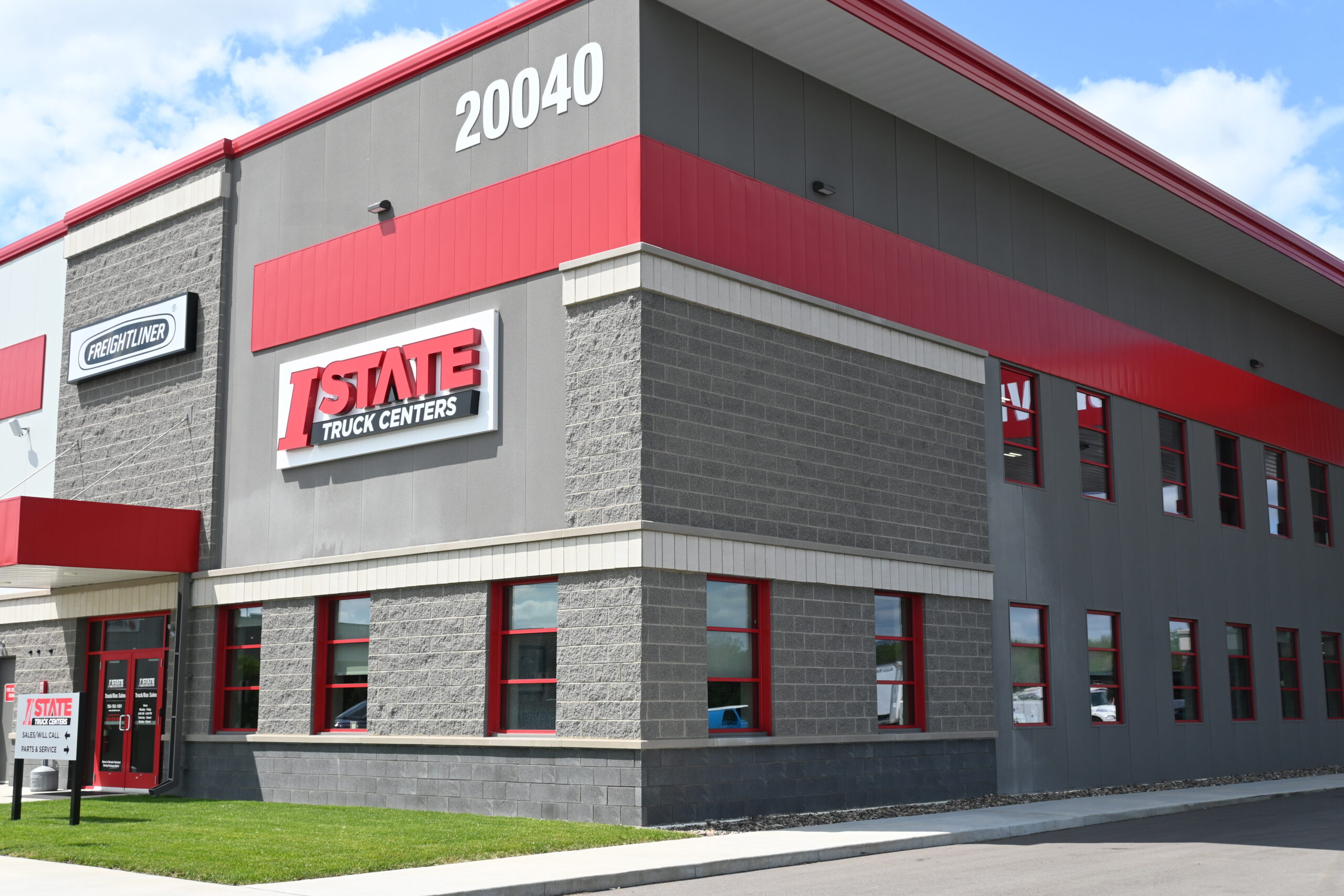 Exterior view of a gray and red commercial building with large windows and a bold 'I STATE Truck Centers' sign; number 20040 on the corner.