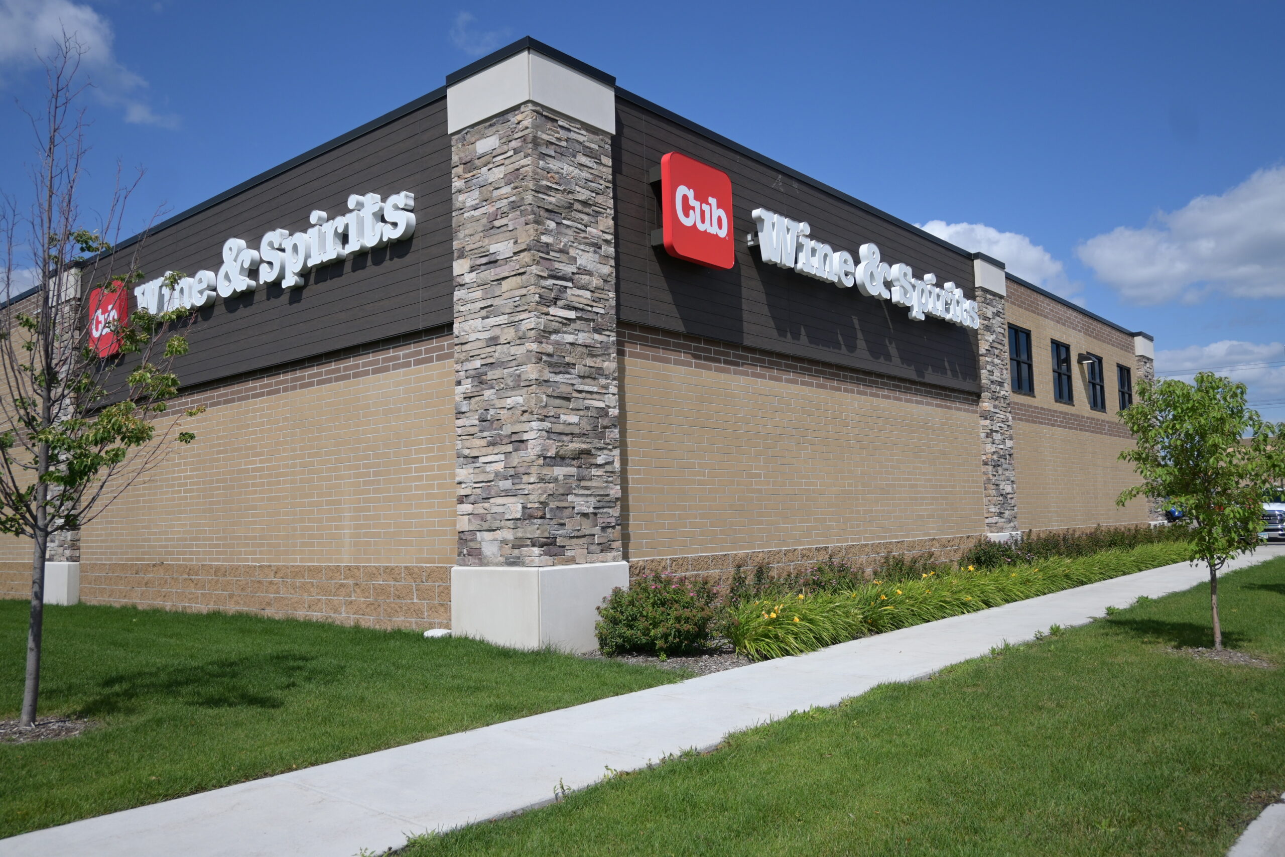 Exterior of Cub Wine & Spirits store with stone columns, brick walls, and a red Cub sign on a sunny day